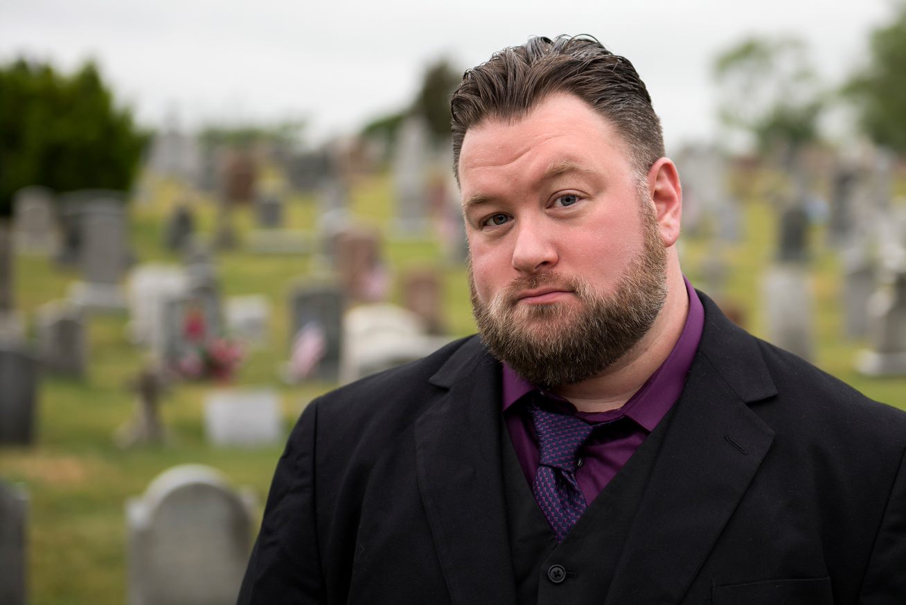 Tim Weisberg pictured in a cemetery wearing a black suit.