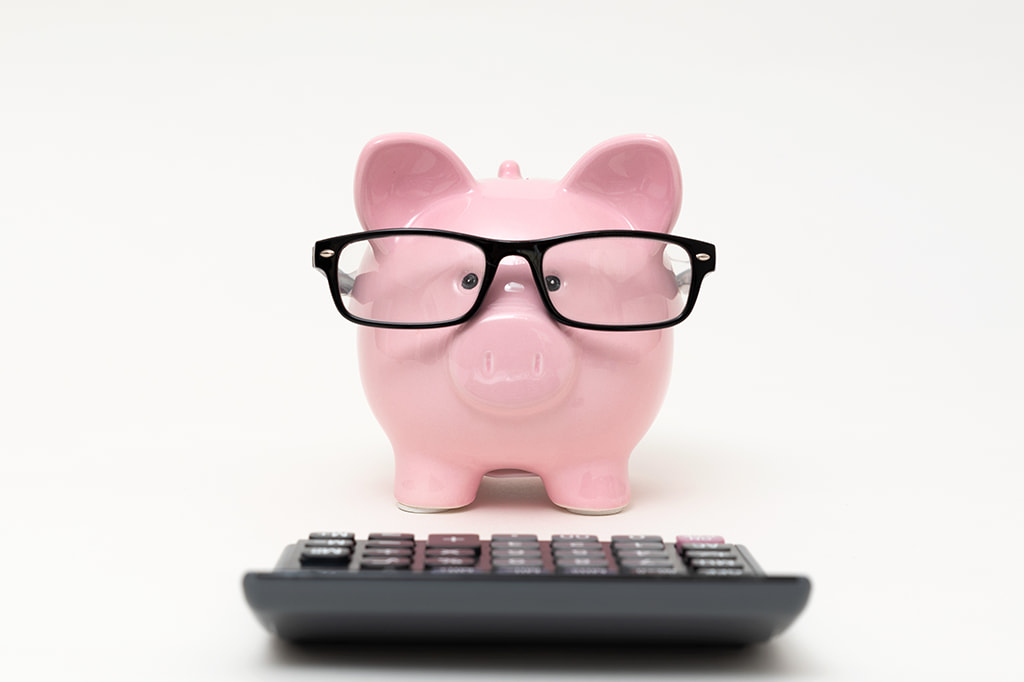 piggy bank wearing glasses stands over a calculator